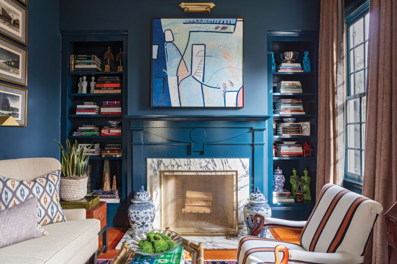 Abstract art, and bold paint colors, like Farrow & Ball “Hague Blue” in the living room, are juxtaposed with antique furnishings.“Brown furniture is very stuffy in general so you have to balance it,” says John.
