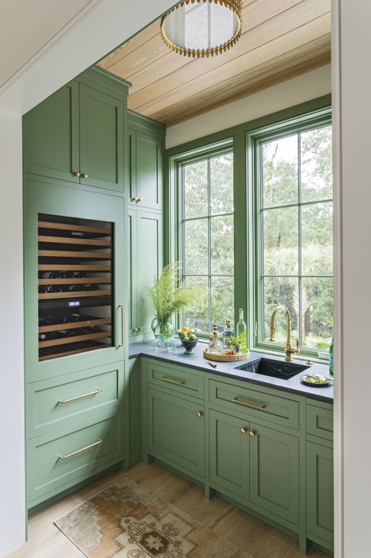 Sage Design: The nearby butler’s pantry, painted in Farrow & Ball “Calke Green,” serves up extra prep space, ample storage, and showstopping looks. “[It] might be my favorite pantry ever,” says Elebash.