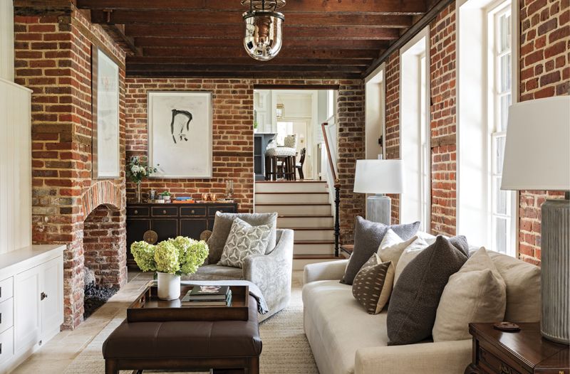 The building, which once served as a kitchen (you can still see knife marks in the fireplace surround), is now connected to the main house. The warm, casual space is used as a family room, with a comfy Verellen sofa, custom crushed velvet swivel chairs, and an Arhaus bar, topped by an original piece by Nicole’s uncle, North Carolina artist Rick Horton.