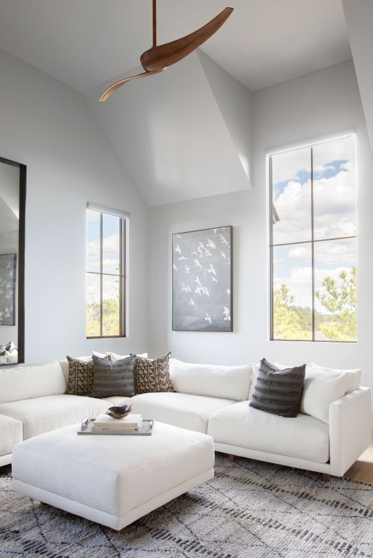 HANG TIME: With a big family of varying ages, having plenty of hang-out spaces was key. In the large, multipurpose den, a Robin Bruce “Neval” sectional and ottoman from Celadon provide ample room to stretch out and watch movies. The Sherwin Williams “Argos” paint adds a hint of blue to mimic the sky captured through the tall windows.