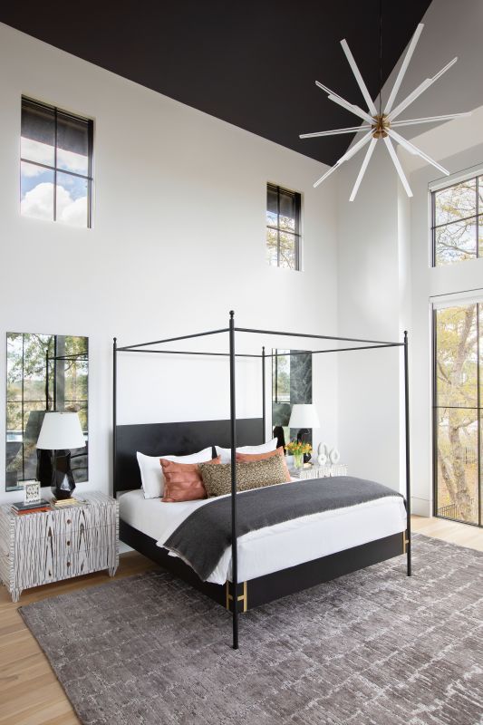 In the homeowners’ bedroom suite they enjoy panoramic views of the marsh from their Doorman Designs bed, handcrafted in New Orleans. A striking contemporary “Photon” chandelier from Visual Comfort highlights the soaring black ceiling, while the hand-knotted Oscillo rug from RH keeps the space grounded. Playful wood nightstands from Italy and black Bayliss table lamps reinforce the monochrome palette.