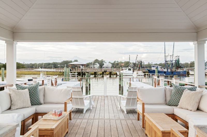 Timeless Teak: Family and friends can relax on the gazebo’s custom Teak Hut sectional, brightened by Bastideaux Artisan Textiles’ “Napili” pillows in “lagoon linen” and “Vertex Linen” outdoor pillows from Ryan Studio.