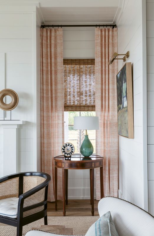 Serene Scene: An antique heirloom demi lune table displays a lamp from Elizabeth Stewart Design; its green hues mimic the lush view. A Mark Sikes caned chair from One Kings Lane sits on a Stark sisal rug, providing a hint of masculinity to the soft palette.