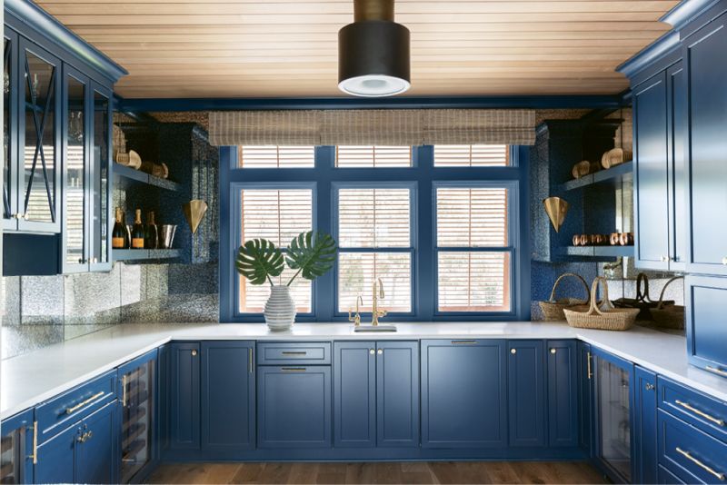 Painted with Sherwin Williams’s brilliant “Rainstorm” and illuminated by the Urban Electric “Jackson” light fixture, the cabinetry by Spartina Kitchens is furnished with custom brass fittings.