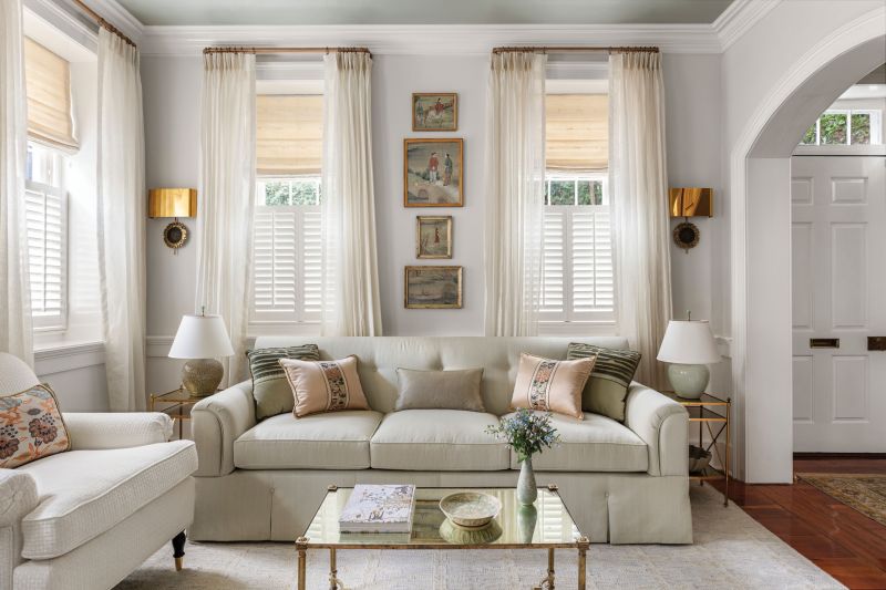 Soothing Sanctuary: The drawing room’s glossy, lacquered ceiling (Benjamin Moore “Misted Green”), soft color palette, and luxurious fabrics create a calm oasis for Claudia. “I love this space. It’s so peaceful to me.” The custom sofa, wrapped in Halsey & Spruce raw silk, is flanked by luminous Sabina Fay Braxton fabric drapes. The antique Swedish secretary cabinet from The Painted Room harkens back to the home’s original era.