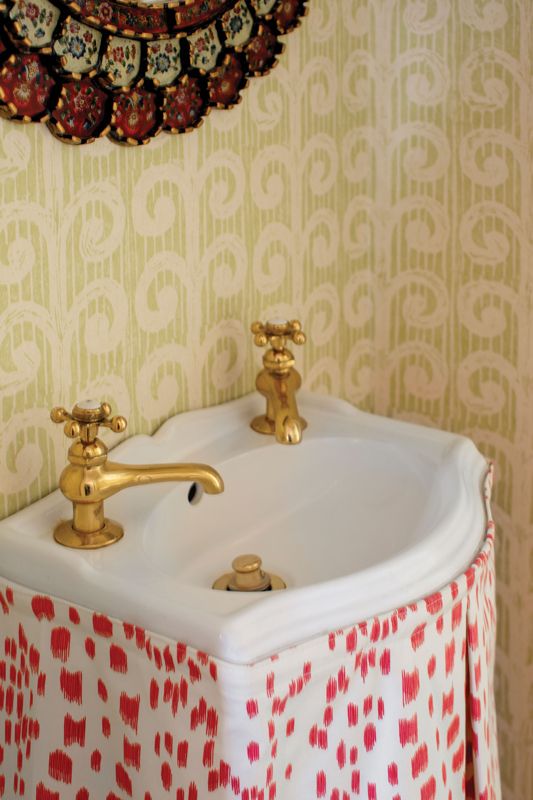 Space Saver: A unique addition to the dining room is this powder room, where a tiny sink and toilet have been squeezed into a closet. Caitlin made the most of this unusual positioning with a playful wallpaper, “Fern” by Blithfield, and sink skirt in Brunschwig & Fils “Le Touches” fabric.