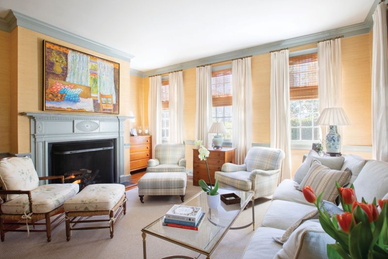 Peachy Keen: Caitlin designed the first-floor living room as a “palette cleanser” for the rest of the home, where bold colors and patterns dominate. The Thibaut “Pearl River”grasscloth wallpaper and white linen drapes provide a soft backdrop for the antique chests and French rush seat chair and ottoman. She had the original wood trim and hand-carved mantelpiece painted in Farrow & Ball “Light Blue” to provide a subtle contrast.