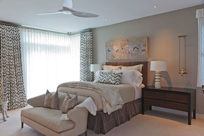 Though the palette is neutral, textured wallpaper and drapes in a patterned fabric by Donghia make a statement in the primary bedroom.