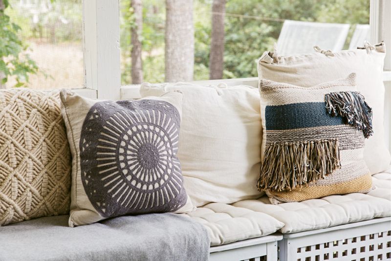 Mix & Match: Therese outfitted bench seating on the screened porch with cushions and woven pillows in soft blue and cream colors.