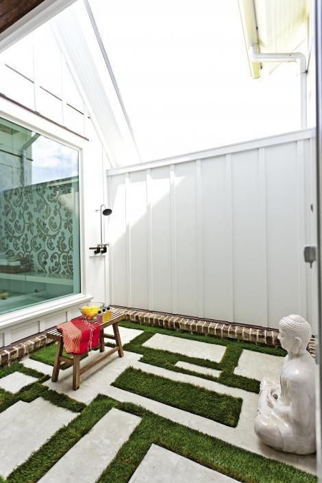 Concrete pavers are set in a geometric pattern in the outdoor shower adjacent to the master bath. The Buddha statue is by Cyan Design.