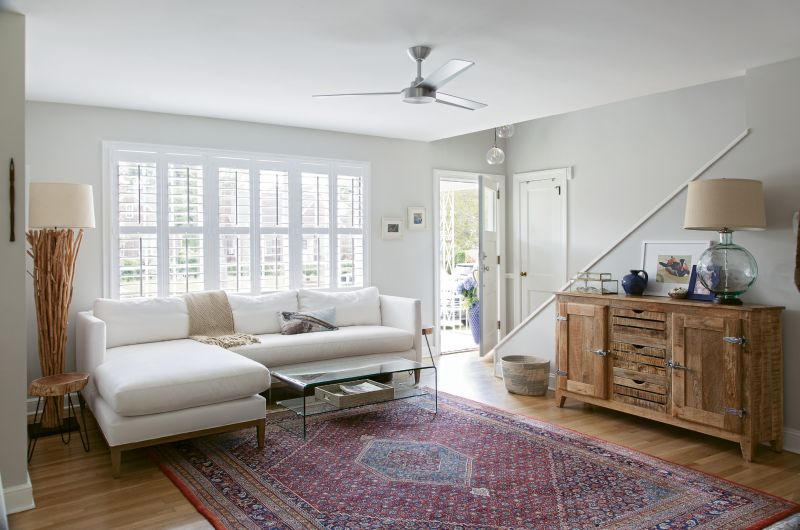 OLD & NEW: The living room is filled with a mix of antiques (the area rug once belonged to Rachel’s grandparents), pieces purchased specifically for the space (like the GDC Home sectional and branch floor lamp from Celadon), and furnishings acquired over time.