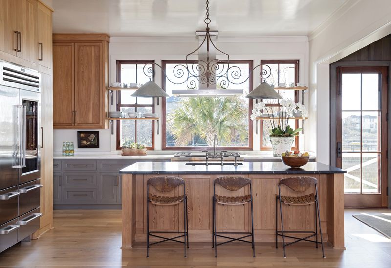 The adjoining kitchen continues the Gallic theme, where a 19th-century French wrought-iron chandelier with zinc shades from Golden & Associates Antiques hangs over the soapstone countertop with a custom-coined edge. Three vintage 1950s rush-and-wood slat bar stools cozy up to the white oak island.