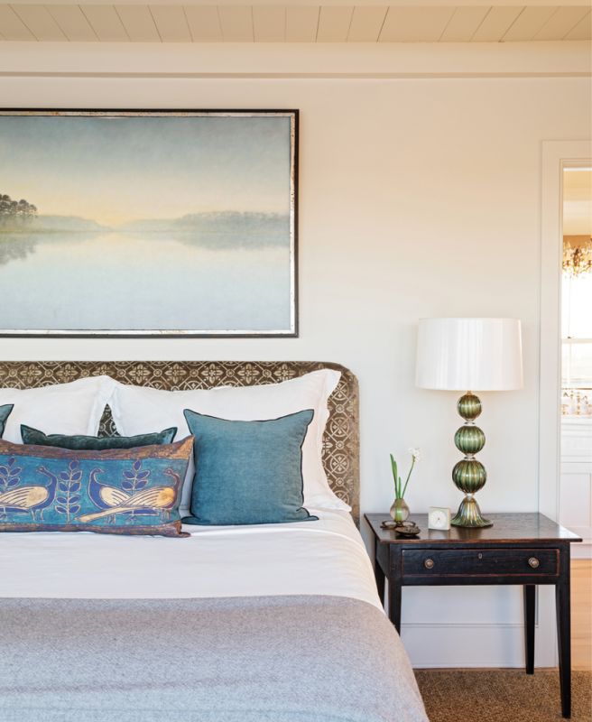 The Bright side: The primary bedroom suite is a study in refined elegance. A soothing landscape painting by local artist Mickey Williams resides above the headboard wrapped in Coleman Taylor “Gatsby Velvet.” Murano glass “Spheres” lamps with lacquered lampshades lined in gold rest atop heirloom bedside tables.