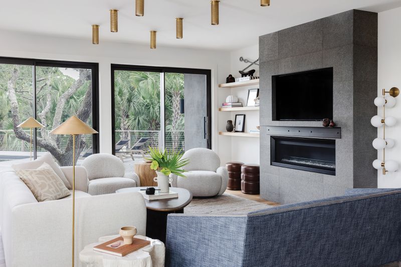 Pops of blue from the Arteriors settee and cabinets painted Farrow & Ball “De Nimes” pepper the white palette where hints of brass in the light fixtures from Visual Comfort and warm woods add an organic feel. Rust-colored Maria Yee dining room chairs surround the Baker Furniture table.