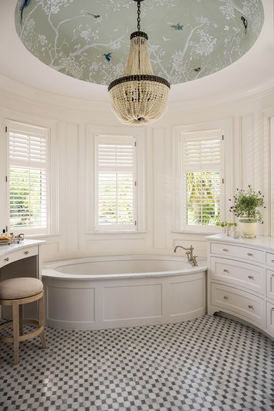 Curves continue in the primary bathroom where a striking Currey & Company chandelier with glass beads hangs from a domed ceiling, painted by local artisan Angela Cabán. A mosaic tile floor of Carrara and Grigio Carnico marble grounds the elegant space.
