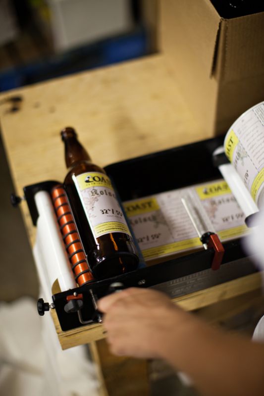 COAST's labeling machine. They label one bottle at a time.