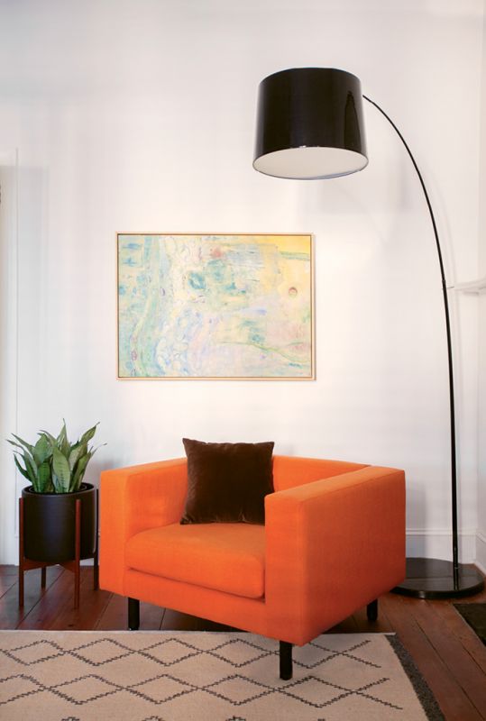The vibrant orange of the Blu Dot “Mono Lounge Chair,” placed before a painting by local artist Diane Jerue