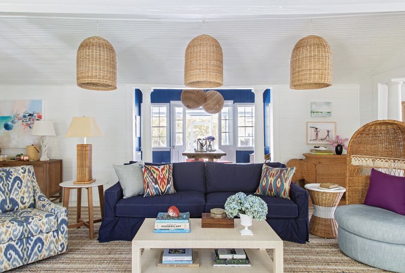 Casual Charms: For the living area, Isbell created three spaces in the former dining room. Serena & Lily wicker pendants and a slip-covered sofa delineate the main seating area, capped by a vintage hooded wicker chair from Chairish.