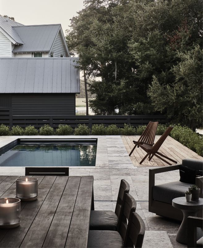 Waterfront Dining: The family shares most meals in the outdoor dining area, surrounded by travertine marble tile with an Ipe wood accent deck. The “Maya” slat-back chairs from CB2, crafted in Mexico out of Tabebuia rosea wood, provide a sculptural perch for lifeguarding in style.