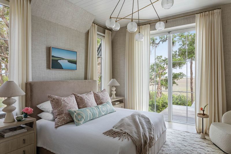 The primary suite is wrapped in soft, muted tones. A Verellen “Hayden” bed covered in Holly Hunt “Pharaoh Morning Light” fabric pairs with Jacob Cooley’s Curving Marsh 2022 oil painting overhead. Japanese paper weave wallpaper and a Marl Moroccan wool rug from Design Within Reach layer texture.