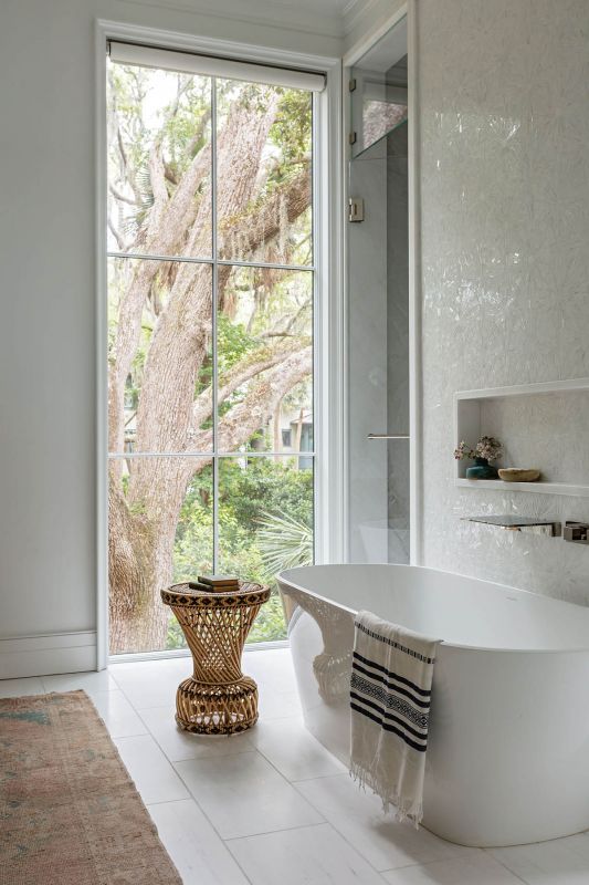 A soaking tub sits at a wall of windows overlooking the live oak canopy.