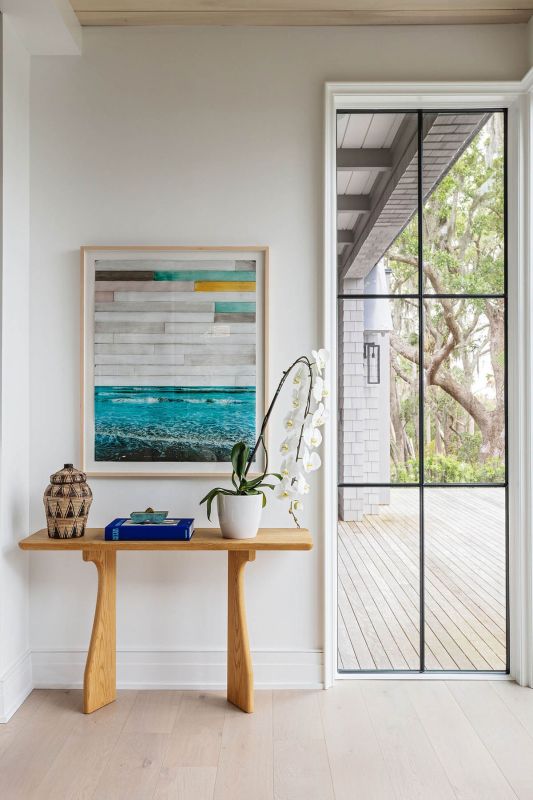 A custom console grounds one of the living room’s quieter corners, where John Folsom’s Study in Blue VI pulls the marsh palette inside.