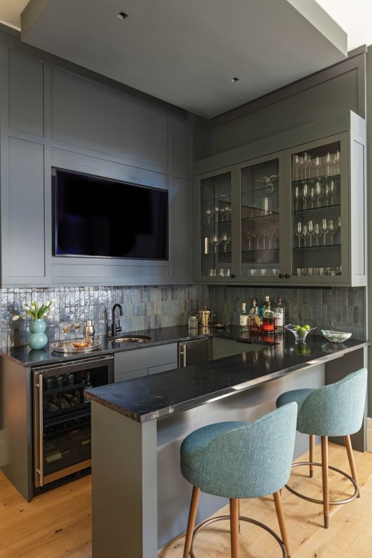 Moody Hues: Painted in Farrow & Ball “Down Pipe,” a deep charcoal with hints of blue, the bar adds an eye-catching element in the bright open living area. A tray ceiling and handmade Moroccan Zellige tile complete the dramatic look.
