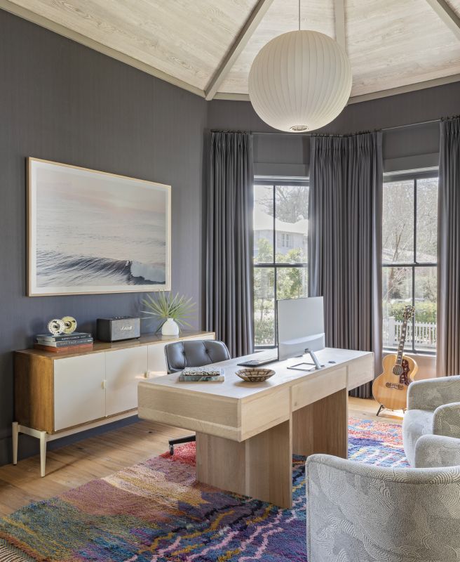 ZOOM ROOM: The octagonal dining room saw little use pre-pandemic, so Jenny turned it into a handsome home office for her husband, Joe. Inky blue Phillip Jeffries grasscloth wallcoverings and drapes fashioned in Romo washable linen in “Linara Blueberry” set a dramatic yet soothing backdrop for the custom white oak desk by carpenter Ryan Mckiernan, vintage Baker Furniture sideboard, and Kate Holstein photograph of Maui’s Honolua Bay from Mount Pleasant’s Heart of Gold Gallery.