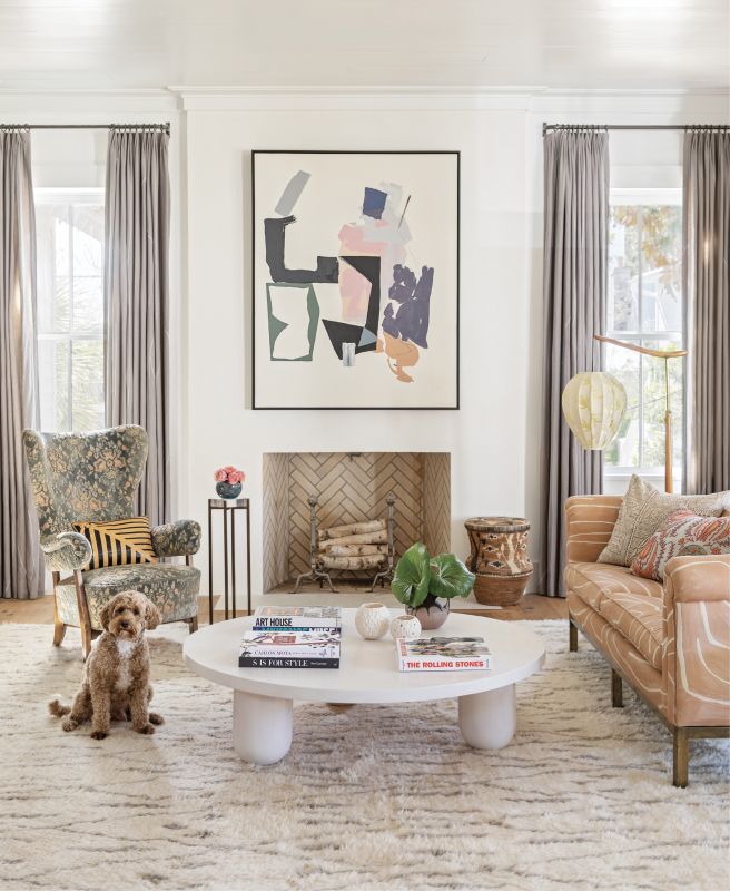 art works: When it comes to art, “Buy what you love” is Jenny’s mantra. “It doesn’t have to match your furniture, fabric, or rug. If you love it, you can put a piece of art anywhere,” says the designer. For her home decor refresh, she rearranged existing art, finding a new home for this abstract Brian Coleman piece in the living room. Centered above the fireplace, it clashes comfortably with the vintage sofa covered in the Kelly Wearstler “Graffito” fabric in “Salmon/Cream.” Pup Rowdy clearly approves.