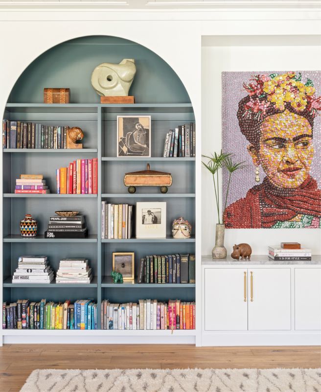 Top Shelf: Adding built-in bookshelves to the living room brought order to the room while providing a pop of color courtesy of Farrow & Ball’s “Inchyra Blue.” The custom design also beautifully showcases local artist Molly B. Right’s bottle-cap homage to Frida Kahlo. A brass and wicker side table from Hollywood at Home and vintage shearling chair from 1stdibs add texture and dimension.
