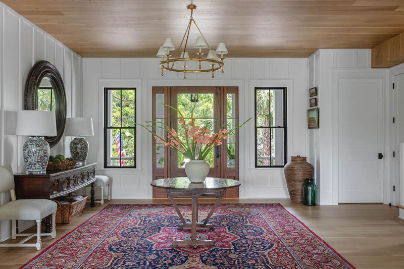 The large antique rug in the expansive entryway has traveled with the couple since their early years together. “I never would have thought it would fit in the hallway of any house!” John says.