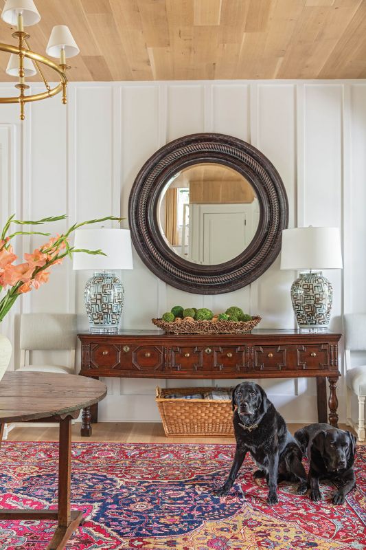 Django and Boogie hold court near an English sideboard discovered in Kentucky. An antique mirror tops the piece, flanked by lamps from Michael Mitchell.