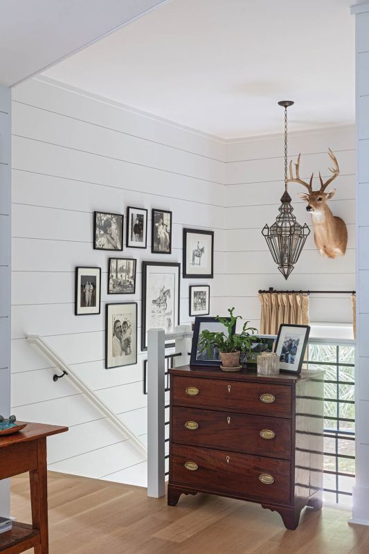 A mahogany antique chest inherited from Jean’s mother anchors the upstairs landing with its curated gallery wall.
