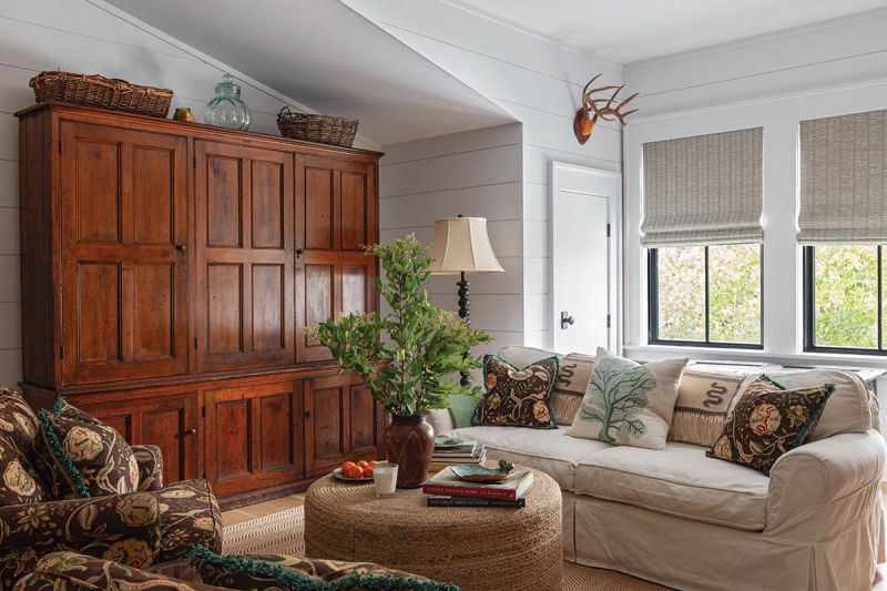 A massive antique linen press that once served as an MIT lab cabinet presides handsomely in the den. The slipcovered sofas and chairs invite relaxation.