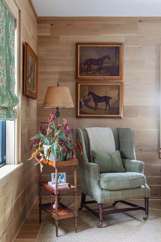 A wingback chair and tiered antique side table are nestled among equine paintings—one from the Paul Mellon estate, others discovered at auction over the years.