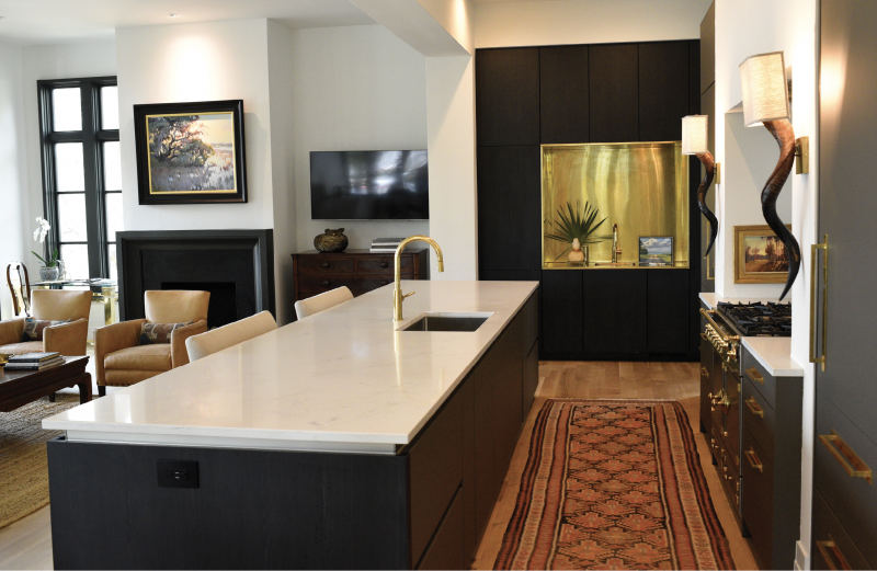 The heart of the home is a stylized modern kitchen that dominates the main, multifunctional living space. A Michelangelo quartz-topped island is a haven of storage and boasts a brass fixture from Moluf’s and matte black Siematic drawers that secret away all the clutter. Kudu horn sconces from online retailer Dira and a vintage rug from 17 South provide warm, earthy tones that lead the eye to the stunning handcrafted French La Cornue range and the showstopping unlacquered brass wet bar.