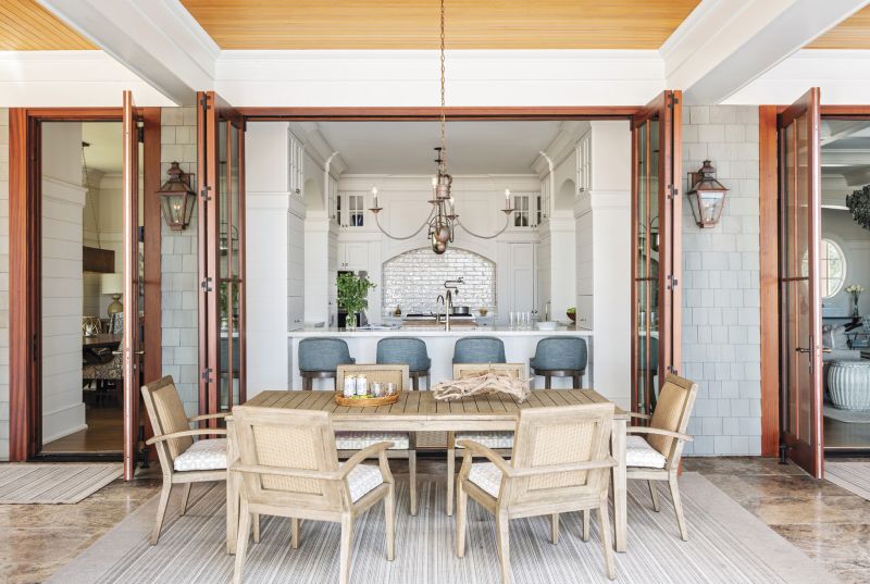 EATING IN & OUT: A floating kitchen anchors the home, tying the indoor and outdoor living spaces together. The alfresco Lloyd Flanders dining table and chairs, purchased at GDC Home, is as accessible to the chef as the formal dining room.