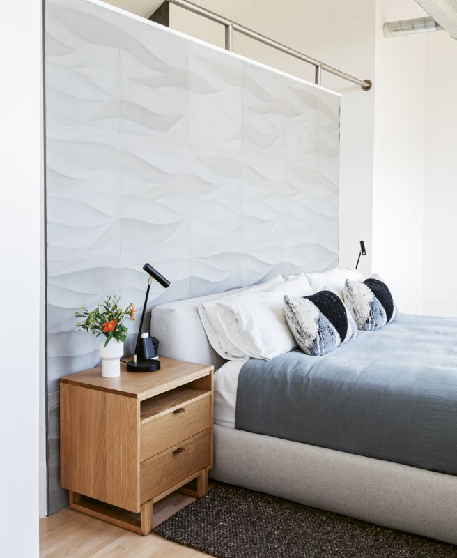 CLEAN & RESTFUL: Simplicity reigns in the master bedroom, where a European platform bed and two oak nightstands are the only furnishings. Handmade Lithuanian bed linens and pillows, as well as a deep gray rug, add tonal interest, while two task lights provide just enough artificial light. “We chose not to have many overhead light fixtures,” explains Steve, “as there’s so much natural light in the house.”
