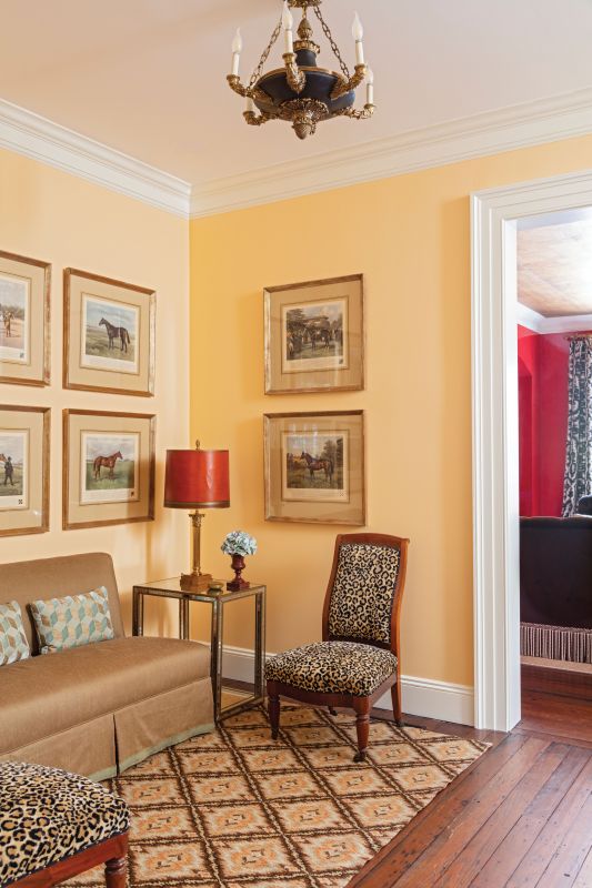 Form & Function: Killian picked Benjamin Moore’s “Pineapple Orange” for the three landings along the dramatic central staircase as it complements the many colors throughout the home while holding its own. Antique slipper chairs, English horse prints, and a vintage needlepoint Stark carpet give the space a useful identity.