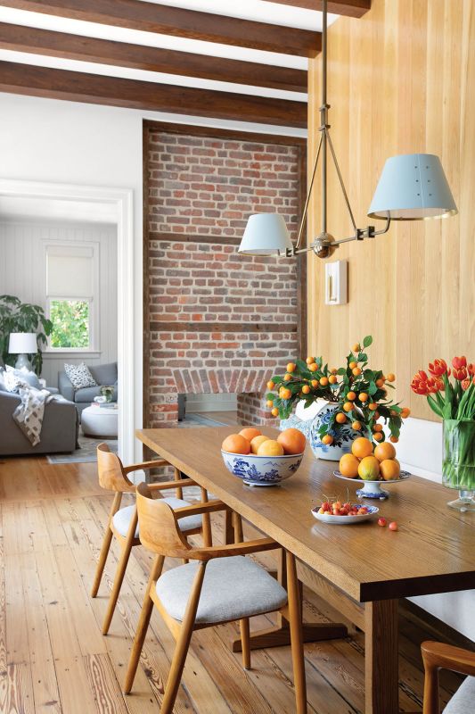 In the dining nook, white oak paneling reflects light from the opposing wall of windows. An Urban Electric “Chiltern” lantern hangs over a Split Woodworks red oak table, where a custom banquette provides ample seating.
