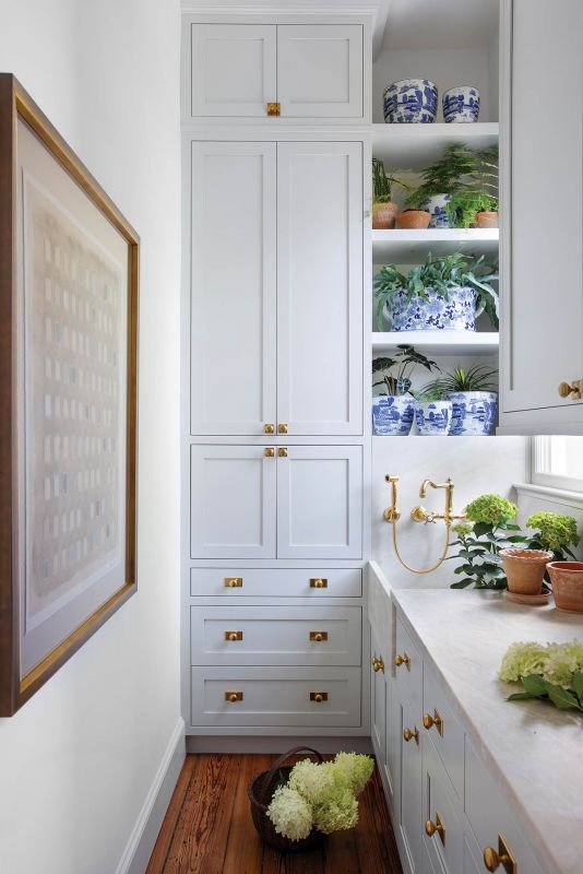 Tucked behind the dining room, the butler’s pantry features a large sink and marble-topped counters highlighted by brass fixtures.