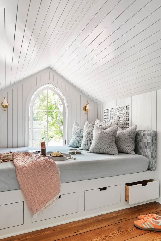 Under the eaves in daughter Ava’s retreat, angled walls left no room for furniture, so built-ins were designed to fit, including a daybed painted in Benjamin Moore “Harbor Haze” and dressed with Emily Daws pillows.