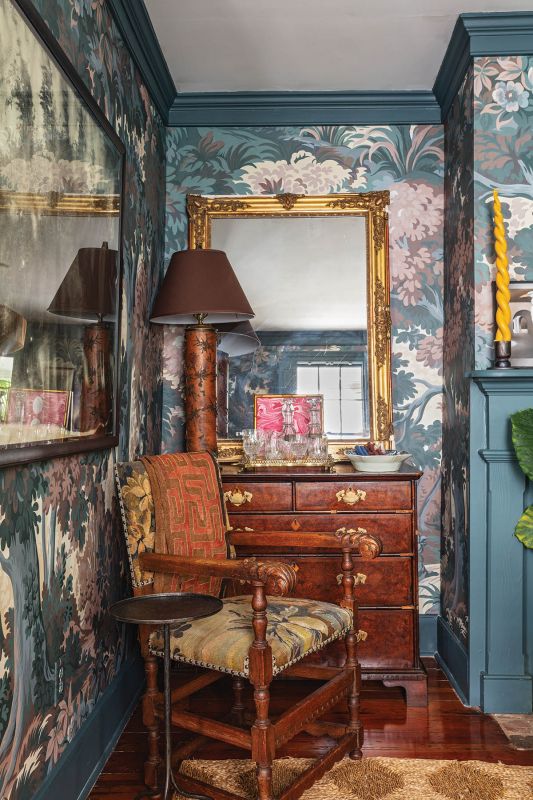 Flanking the central fireplace, two antique chairs covered in a French Aubusson tapestry create distinct vignettes: one beside an English chest repurposed as a bar...