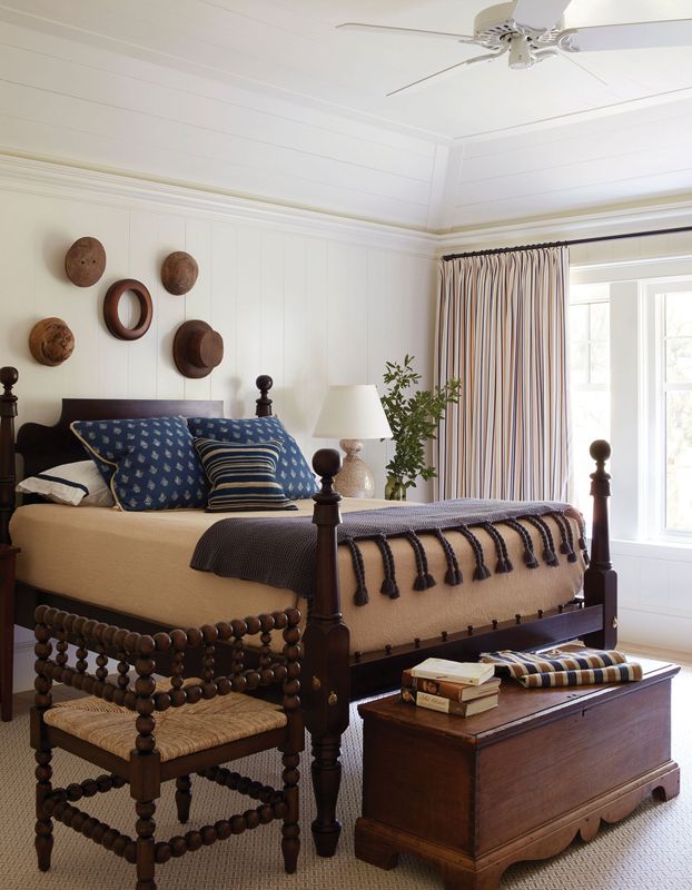An antique bed and Mecox stool tie in with an antique trunk and hat moulds hanging on the wall to create handsome quarters.