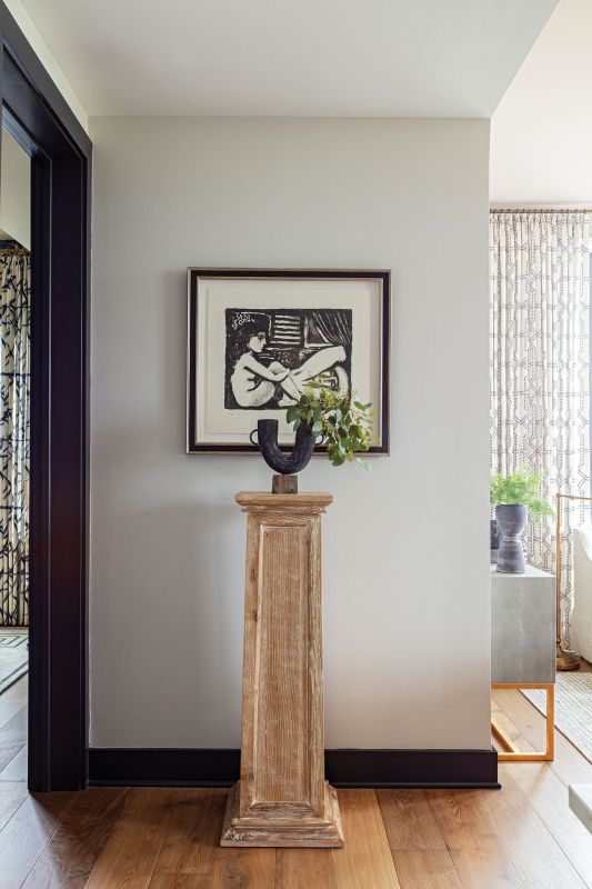 A pedestal from CB2 showcases a Kalalou vase backed by an original painting by Dutch contemporary artist Erik Renssen.