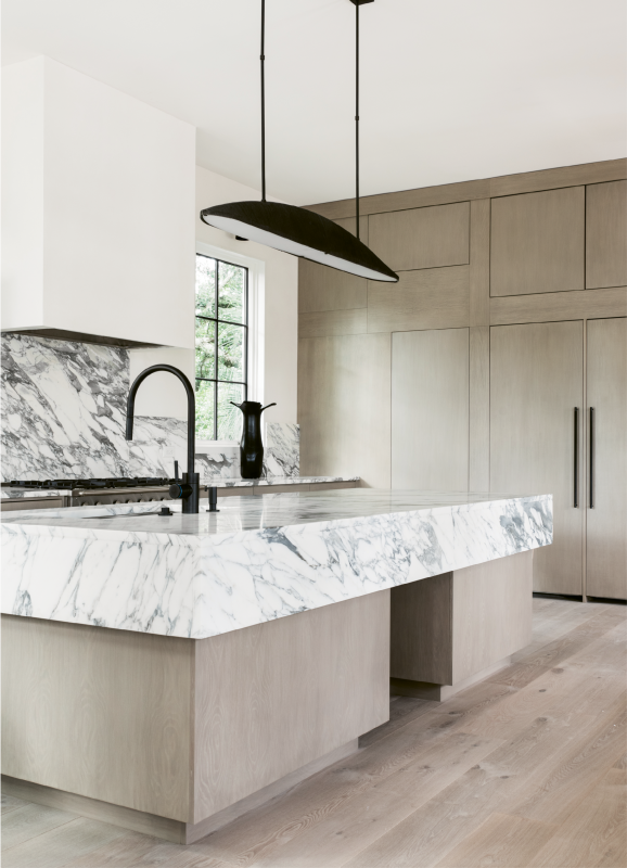 In the light and airy kitchen, white marble countertops with bold black veining make a strong visual impact.