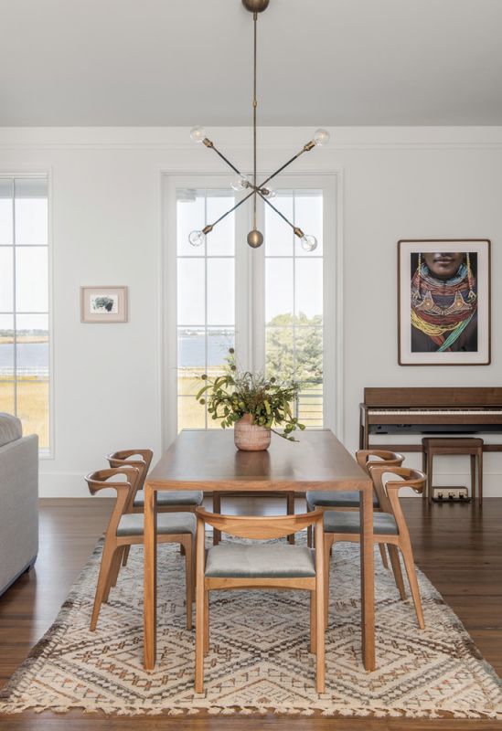Dining in Style: Separating the kitchen from the living room, the dining area features a Ligne Roset “Eaton” table surrounded by Brazilian wood “Duda” chairs from Sossego Design. A vintage Moroccan rug from Elegant Nomad covers the old-growth pine floors that connect the spaces. The scene is illuminated by a “Highwire” fixture from the New York-based Apparatus Studio.